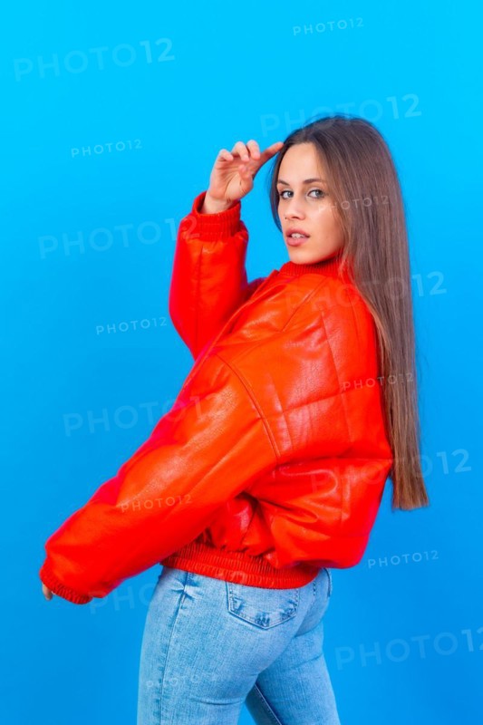 Close up portrait of young caucasian woman in red windbreaker isolated on blue studio background
