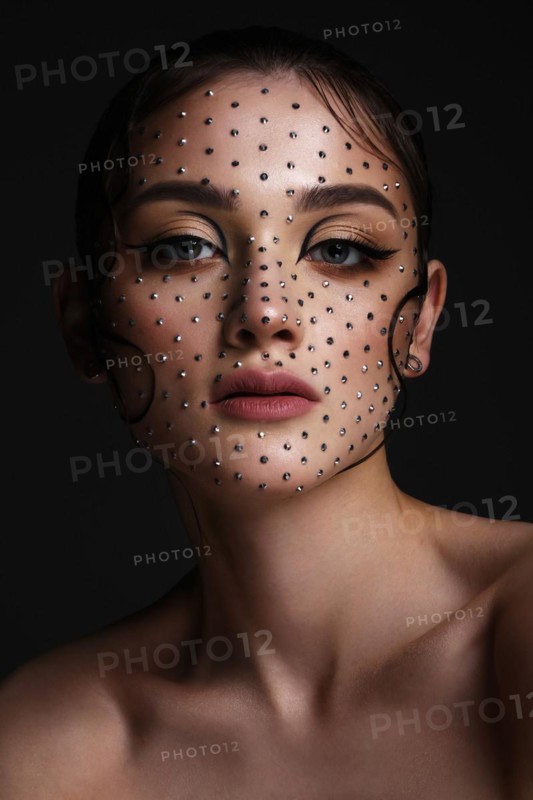 Beautiful woman with creative hairstyle and makeup with rhinestones. Beauty face. Photo taken in the studio