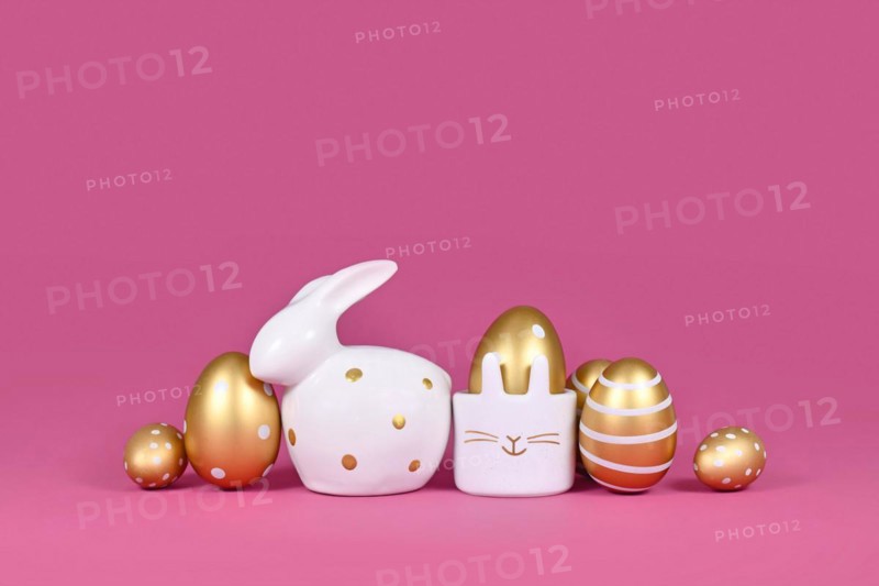 Golden Easter eggs painted with stripes and dots and bunny on pink background with copy space