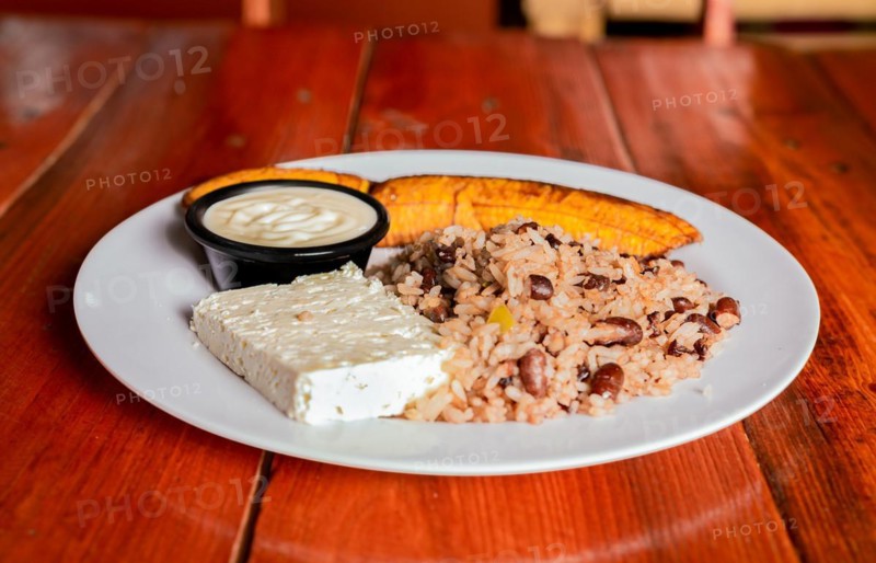 Traditional Gallo Pinto meal with maduro and cheese served. Gallopinto plate with cheese and maduro on wooden table. Nicaraguan food concept