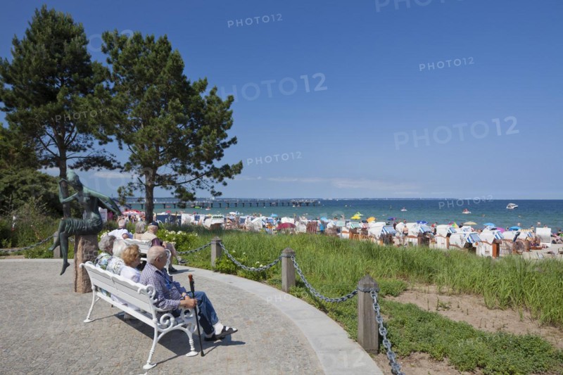 Tourists sitting on bench and looking over the beach at Timmendorfer Strand
