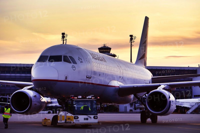 Agean Airlines aircraft towing in front of Terminal 2 in the sunset