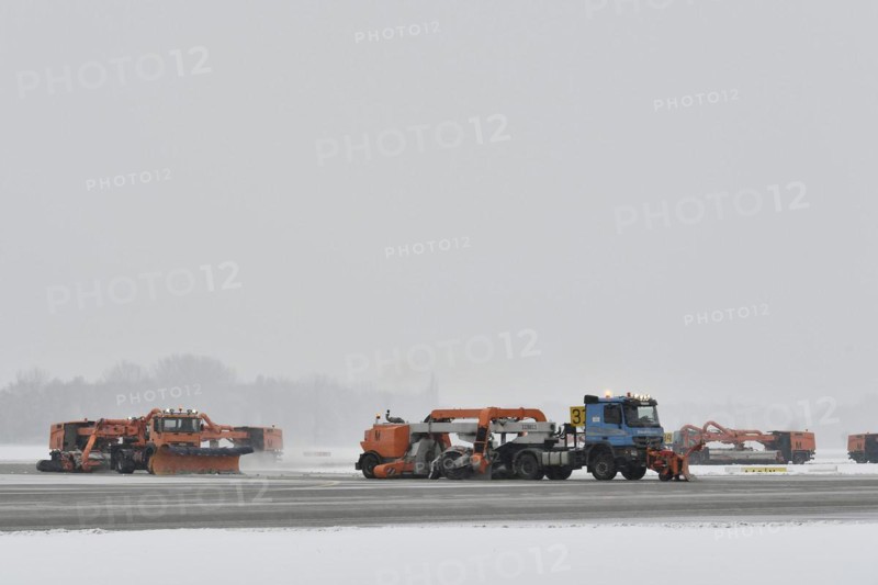 Road sweepers and snow ploughs clear snow on the taxiways and Runway North
