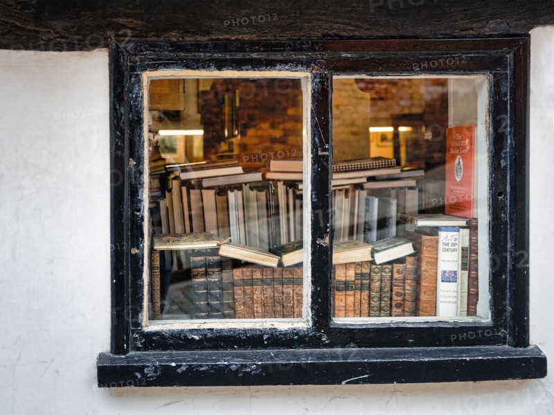 View through an old window on stacks of books