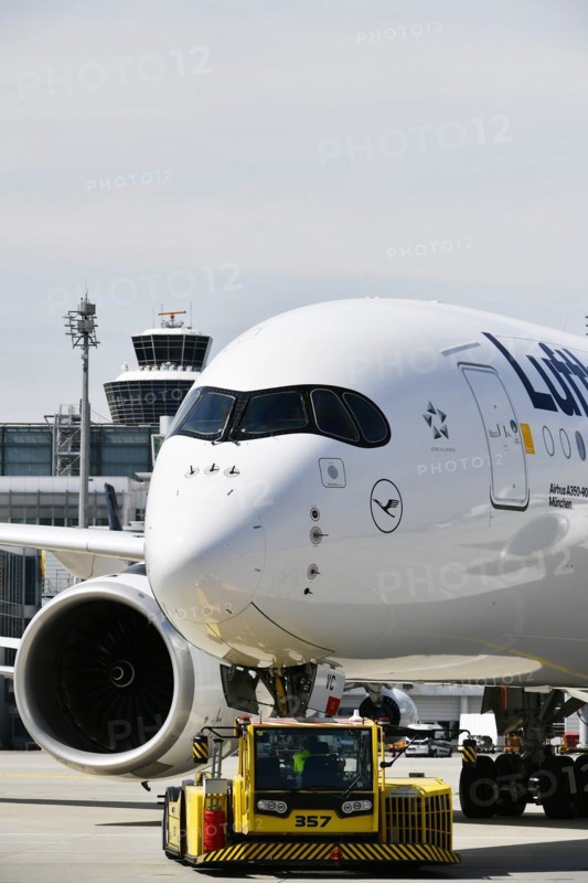 Lufthansa Airbus A350-900 towing with push-back truck in front of Terminal 2 with tower