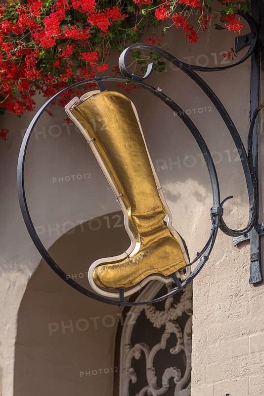 Gold-coloured boot as nose sign of a shoe shop