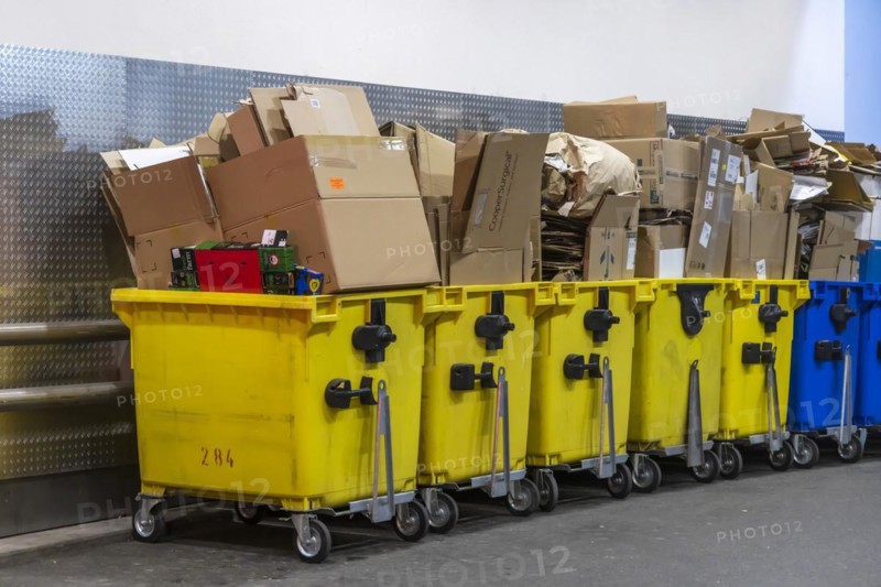 Full yellow waste containers with waste paper and cardboard