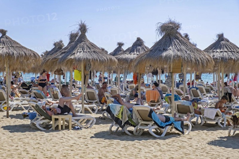 Sunbathers on reclining chairs under parasols on Golem beach