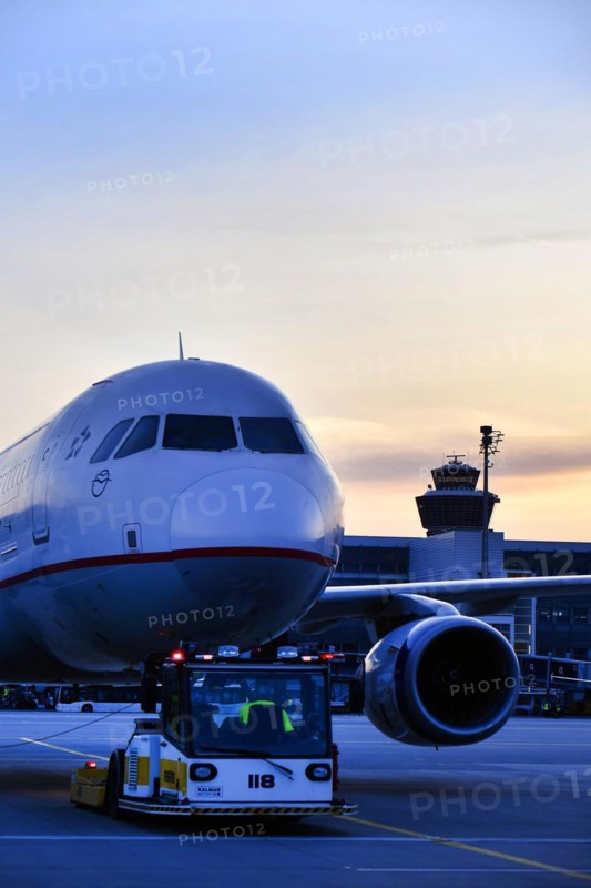 Agean Airlines aircraft towing in front of Terminal 2 in the sunset