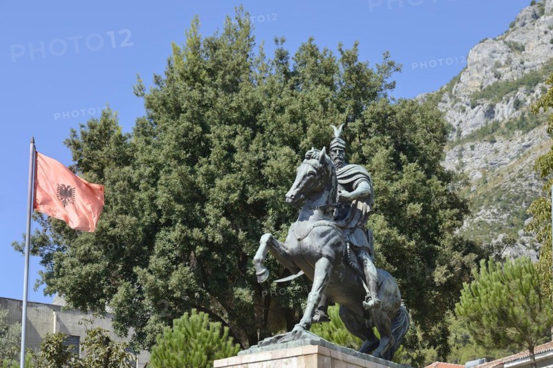 Monument to Skanderbeg and waving flag in front of Kruja or Kruje fortress