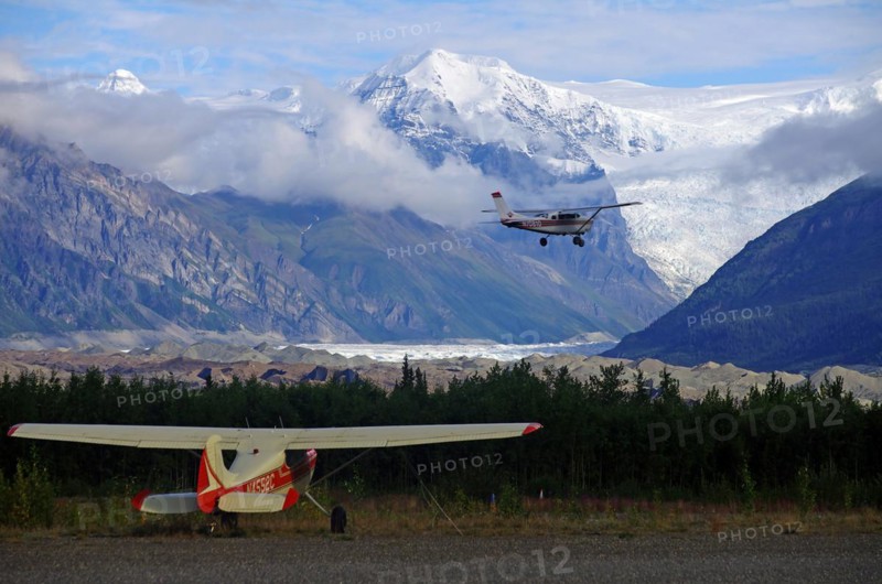 Two small bush planes in front of huge glaciers