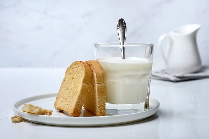 Rusk and glass of milk with spoon