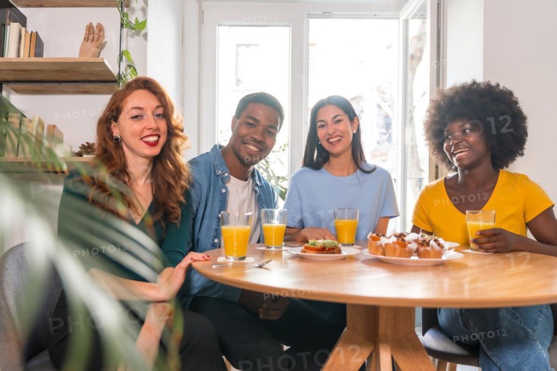 Portrait of multi-ethnic friends having a breakfast with orange juice and muffins at home
