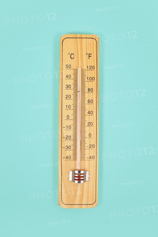 Wooden thermometer on green background
