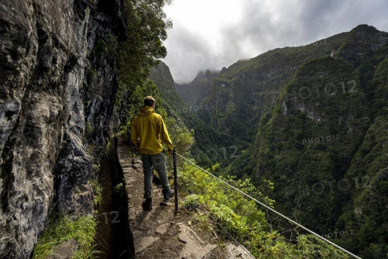 Hikers on a narrow path along a levada, view of forested mountains, Levada do Caldeirao Verde, Parque Florestal das Queimadas, Madeira, Portugal, Europe