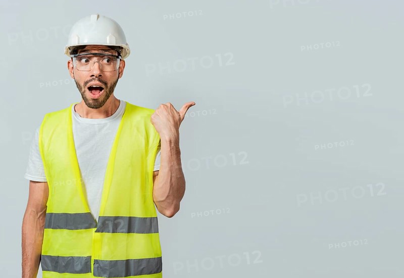 Surprised engineer pointing to the side. Surprised face construction worker pointing at an advertisement. Engineer man pointing to side. Surprised face engineer pointing finger to the right