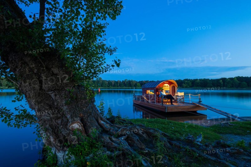 Man sitting in the blue hour on a houseboat, house raft, in front of the island Kiehnwerder, Breitlingsee, Brandenburg an der Havel, Havelland, Brandenburg, Germany, Europe