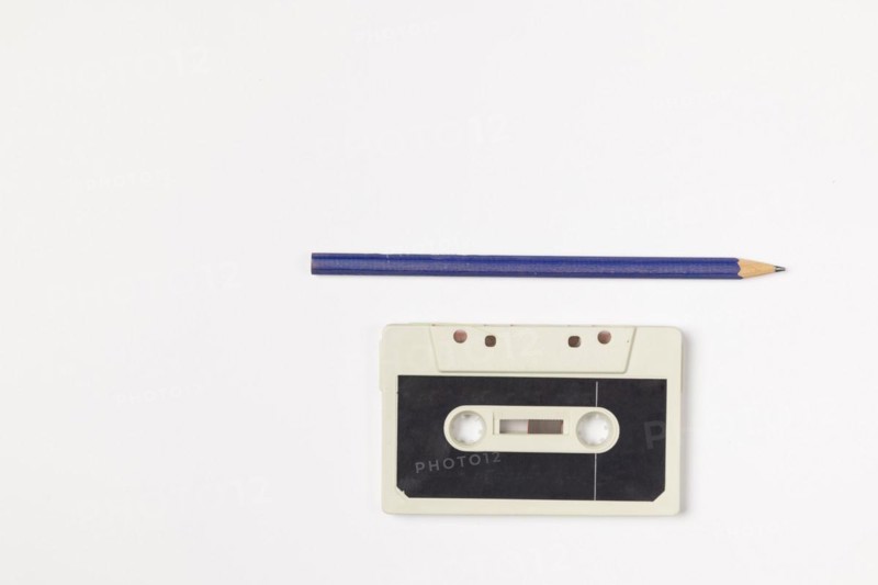 Old compact cassette with pencil on white background, copy room