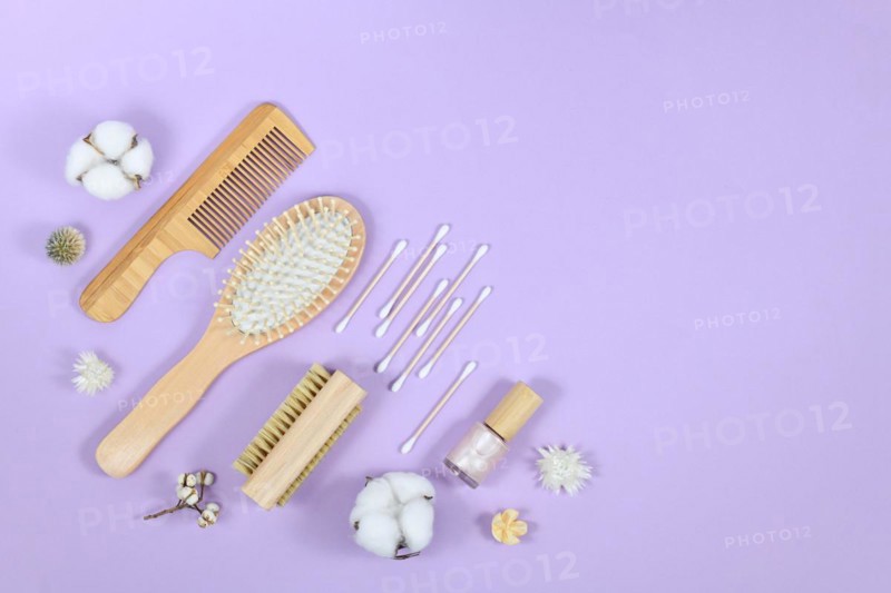 Eco friendly wooden beauty and hygiene products like comb and soap in corner of purple background with copy space