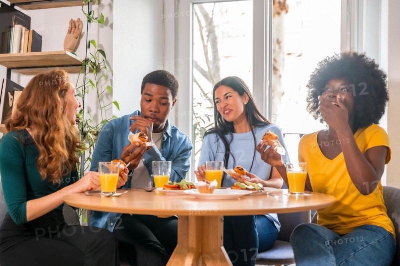 Friends at a breakfast with orange juice and muffins at home, having fun in domestic life