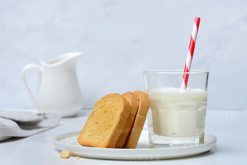 Rusk and glass of milk with drinking straw