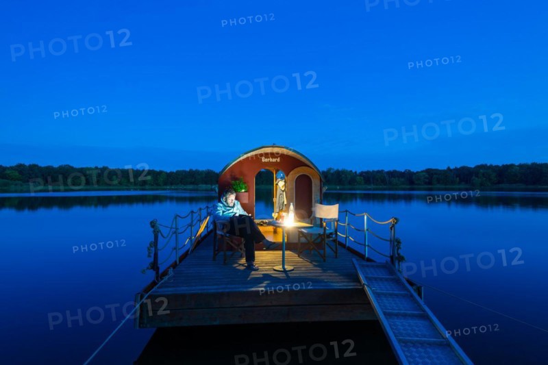 Man sitting in the blue hour on a houseboat, house raft, in front of the island Kiehnwerder, Breitlingsee, Brandenburg an der Havel, Havelland, Brandenburg, Germany, Europe