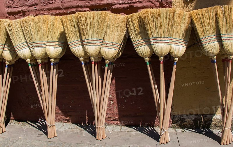 Set of yellow straw broom in a bazaar