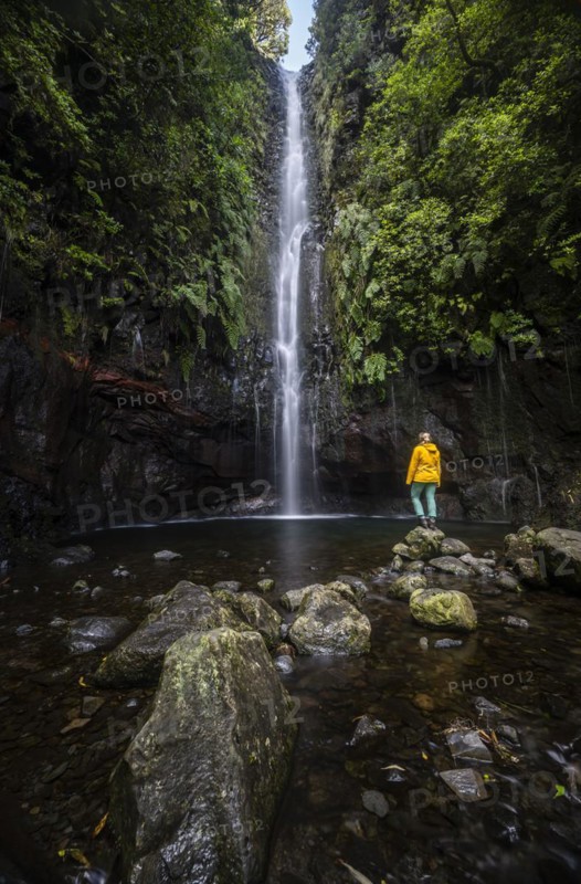 Young woman standing by the river and waterfall Cascata das 25 Fontes, long exposure, Rabacal, Paul da Serra, Madeira, Portugal, Europe