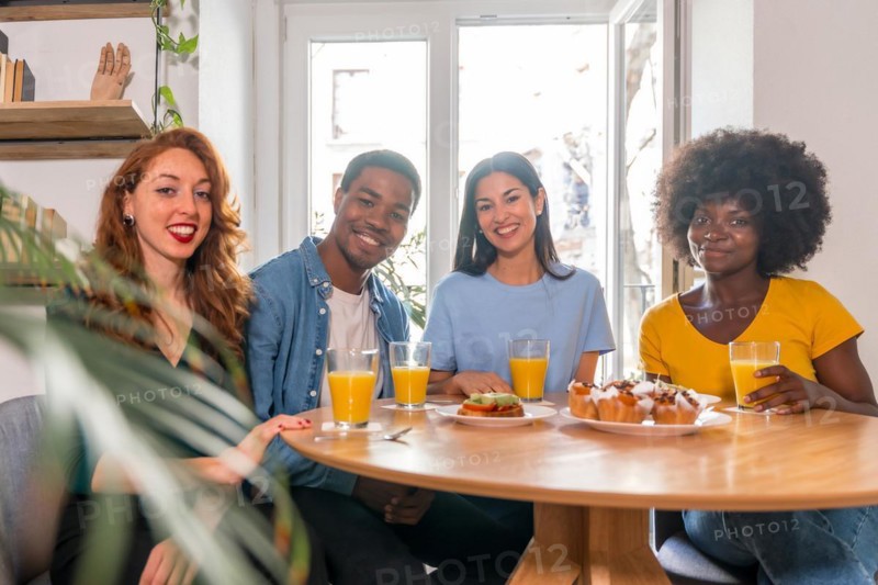Portrait of multi-ethnic friends having a breakfast with orange juice and muffins at home