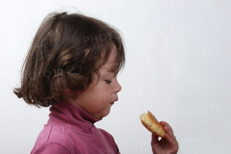 A young girl eating a bun