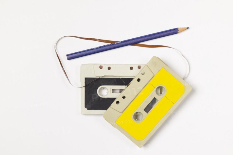Old compact cassettes with pencil on white background, copying room