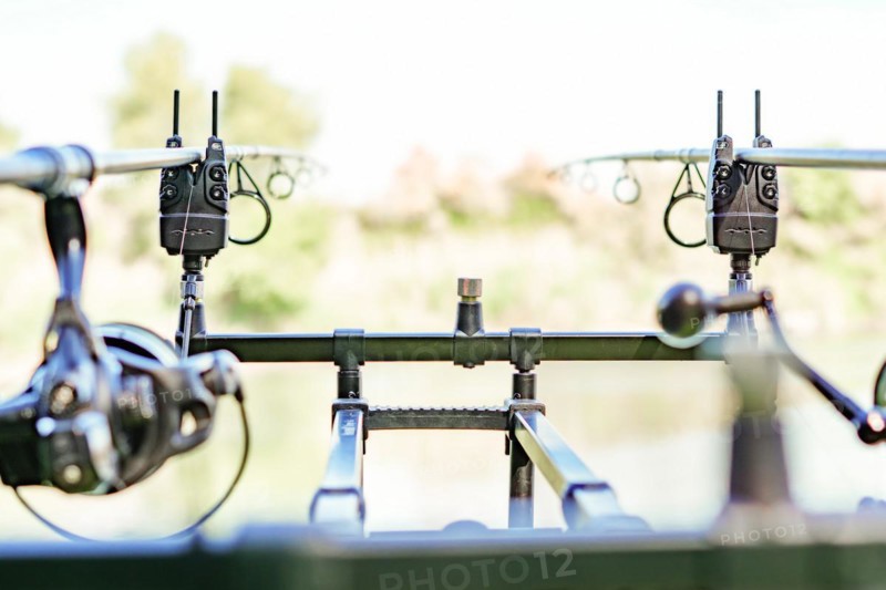 Close-up of a rod holder with alarms and two rods with their reels in fishing action
