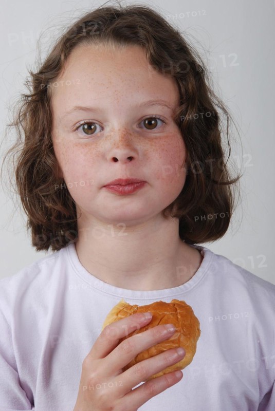 A young girl eating a bun