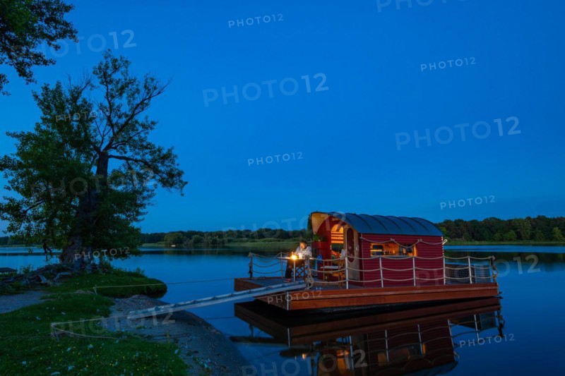 Man sitting in the blue hour on a houseboat, house raft, in front of the island Kiehnwerder, Breitlingsee, Brandenburg an der Havel, Havelland, Brandenburg, Germany, Europe