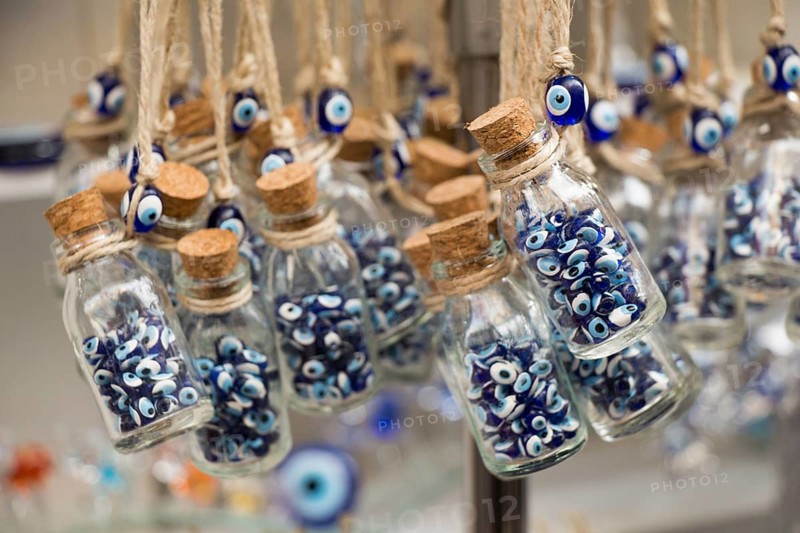 Little transparent glass bottle filled with blue evil eye beads