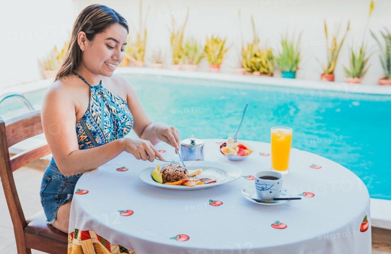 Woman on vacation having breakfast near swimming pool. Breakfast concept near swimming pool, Smiling girl having breakfast near the swim pool