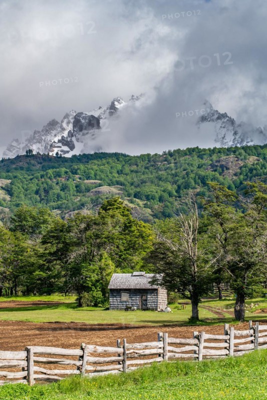 Shingle-roofed wooden house in front of snow-capped mountains, Villa Cerro Castillo, Cerro Castillo National Park, Aysen, Patagonia, Chile, South America