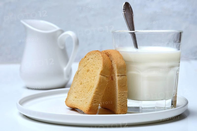 Rusk and glass of milk with spoon