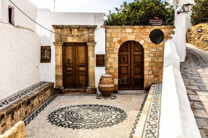 Old wooden doors with pebble mosaics on the floor, winding streets with white houses, Lindos, Rhodes, Greece, Europe