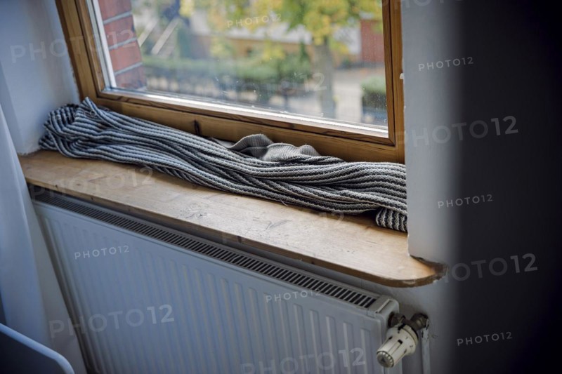 Symbolic photo on the subject of a cold flat. A blanket lies on the windowsill in front of a poorly insulated window to protect against cold air. Berlin, Berlin, Germany, Europe