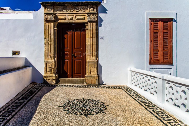 Old wooden doors with pebble mosaics on the floor, winding streets with white houses, Lindos, Rhodes, Greece, Europe