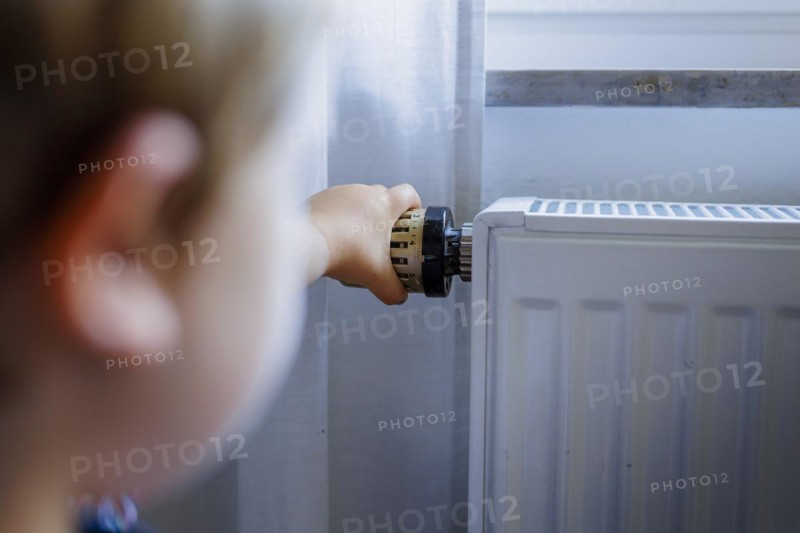 Bonn. Toddler turns the heating thermostat. Bonn, Germany, Europe