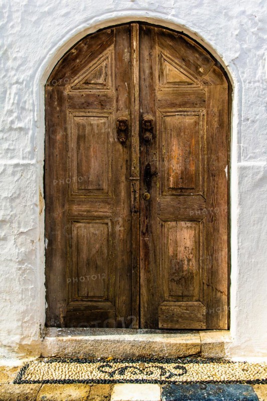 Old wooden doors with pebble mosaics on the floor, winding streets with white houses, Lindos, Rhodes, Greece, Europe
