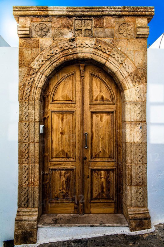 Old wooden doors with pebble mosaics on the floor, winding streets with white houses, Lindos, Rhodes, Greece, Europe