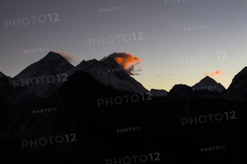 Daybreak at Gokyo Ri. Three clouds mark three eight-thousanders, Mount Everest on the left, Lhotse in the middle and Makalu on the right-hand-side in the greater distance. Silhouette of the mountain ridges. Gokyo Trek, Khumbu, the Everest Region, Himalayas. Sagarmatha National Park, a UNESCO World Heritage Site. Solukhumbu, Nepal, Asia