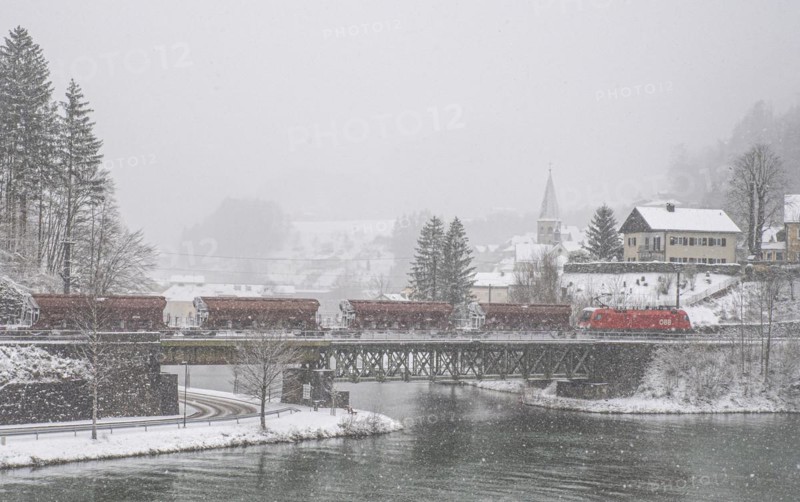 OeBB goods train loaded with ore and the electric locomotive Taurus on the drawbridge over the river Enns in the snowy landscape of Reichraming, Upper Austria, Austria, Europe