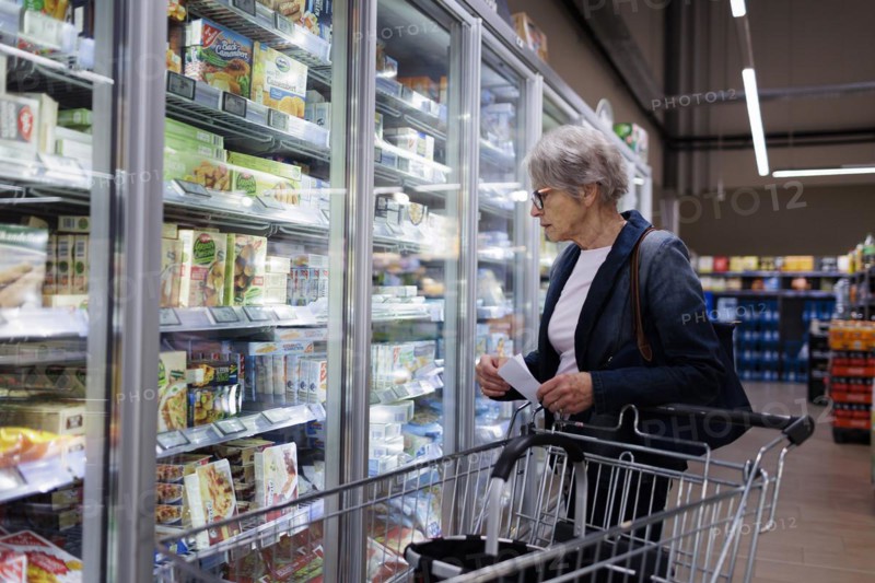 Elderly woman shopping in supermarket. Radevormwald, Germany, Europe