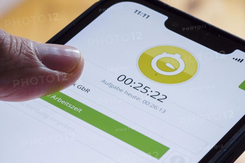 Symbolic photo on the subject of digital time recording. The Clockodo app is used to record an employees working hours on a smartphone. Berlin, Berlin, Germany, Europe