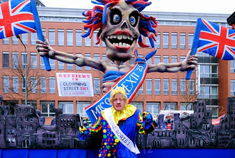 Theme float by Jaques Tilly: Carnivalist with Boris Johnson mask in front of the Brexit float, Rosenmontagszug in Duesseldorf, North Rhine-Westphalia