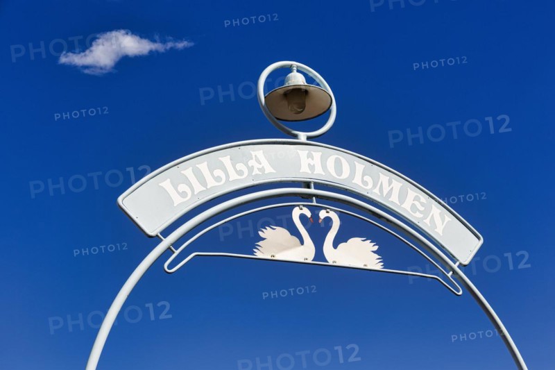 Sign with two swans and inscription Lilla Holmen against blue sky, entrance to park with beach, Mariehamn, Aland, Aland Islands, Alandinseln, Finland, Europe